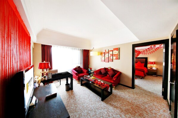 Una habitación de hotel con una decoración en rojo y blanco, un sofá, una mesa de centro y un televisor.