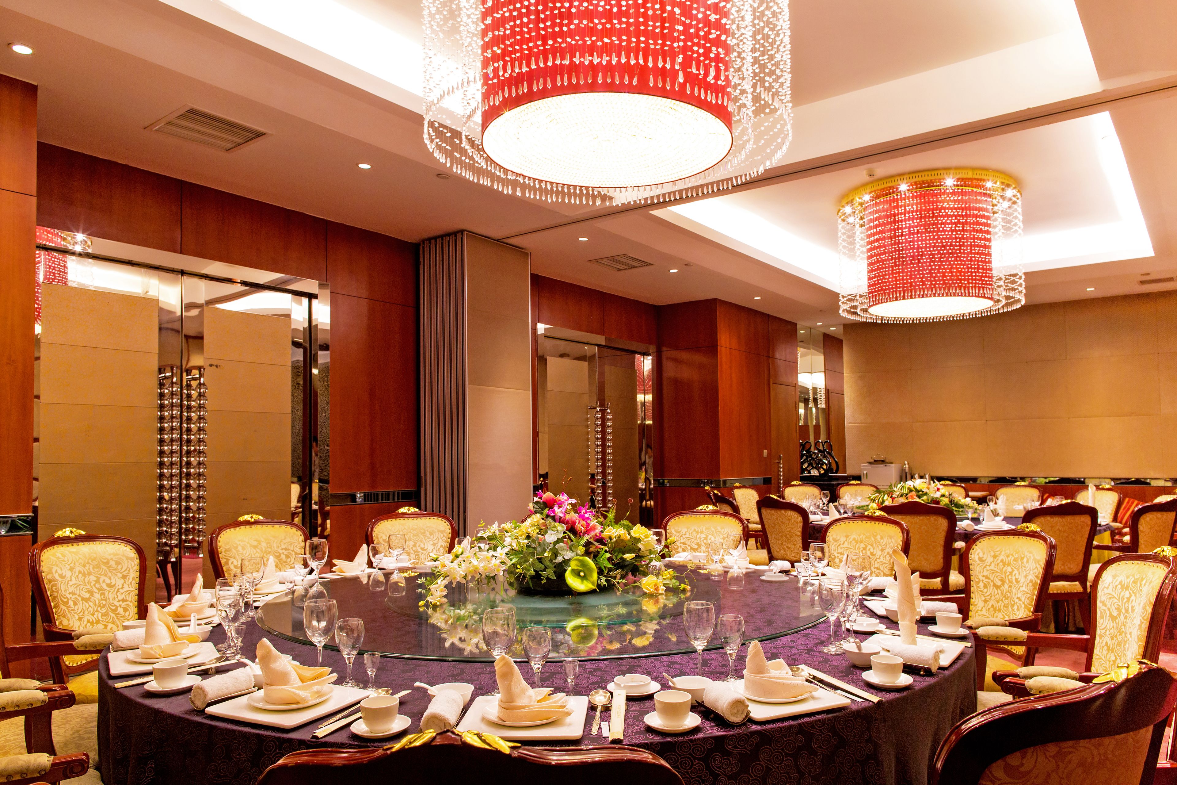 A conference room with a round table, chairs, and a large chandelier.