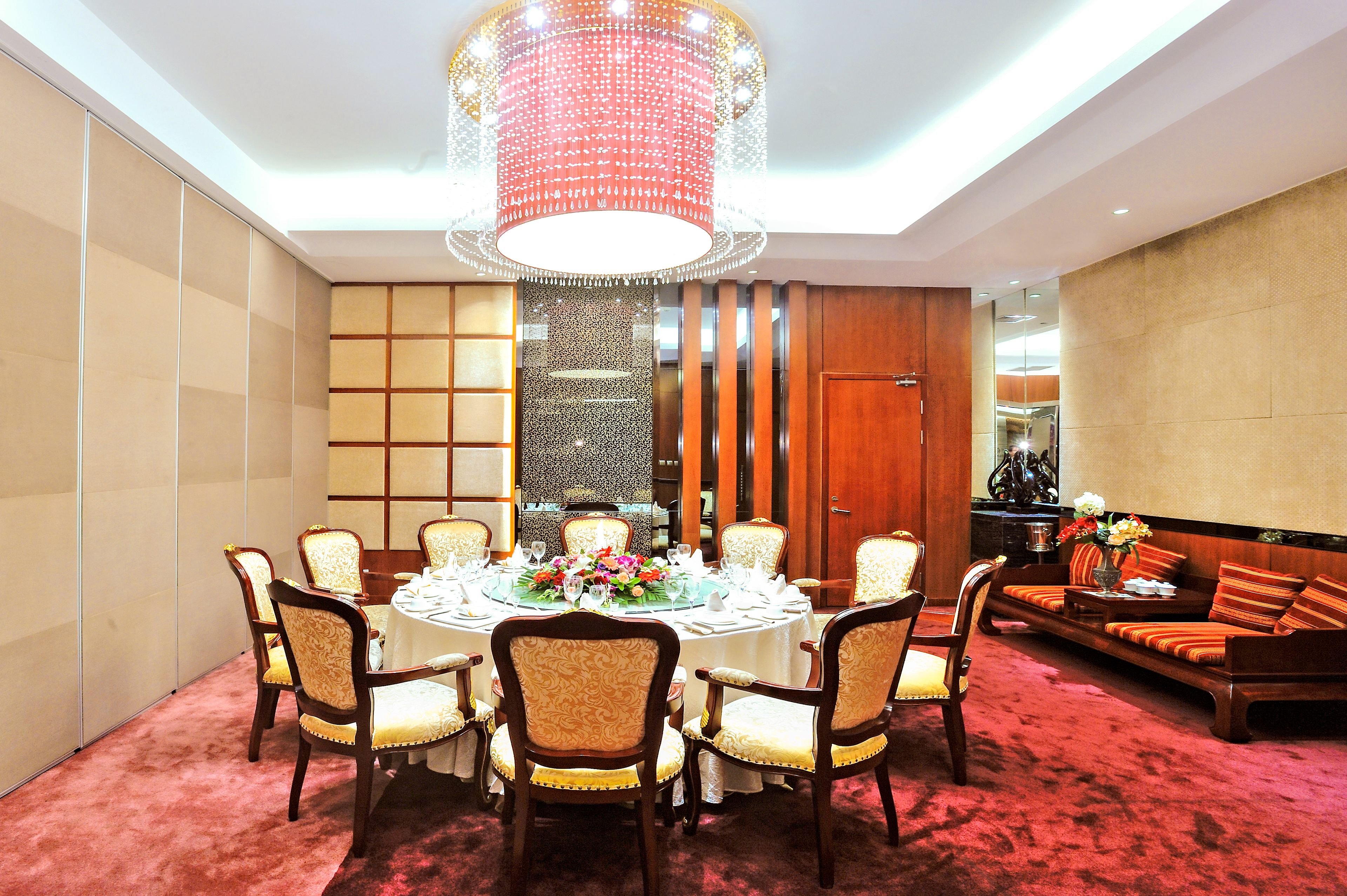 A dining area with a round table set for six, surrounded by upholstered chairs.