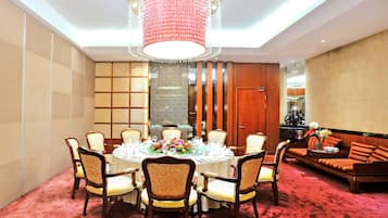 A dining area with a round table set for six, surrounded by upholstered chairs.