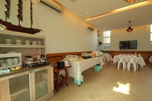 A dining area with a buffet setup, a coffee station, and a television mounted on the wall.