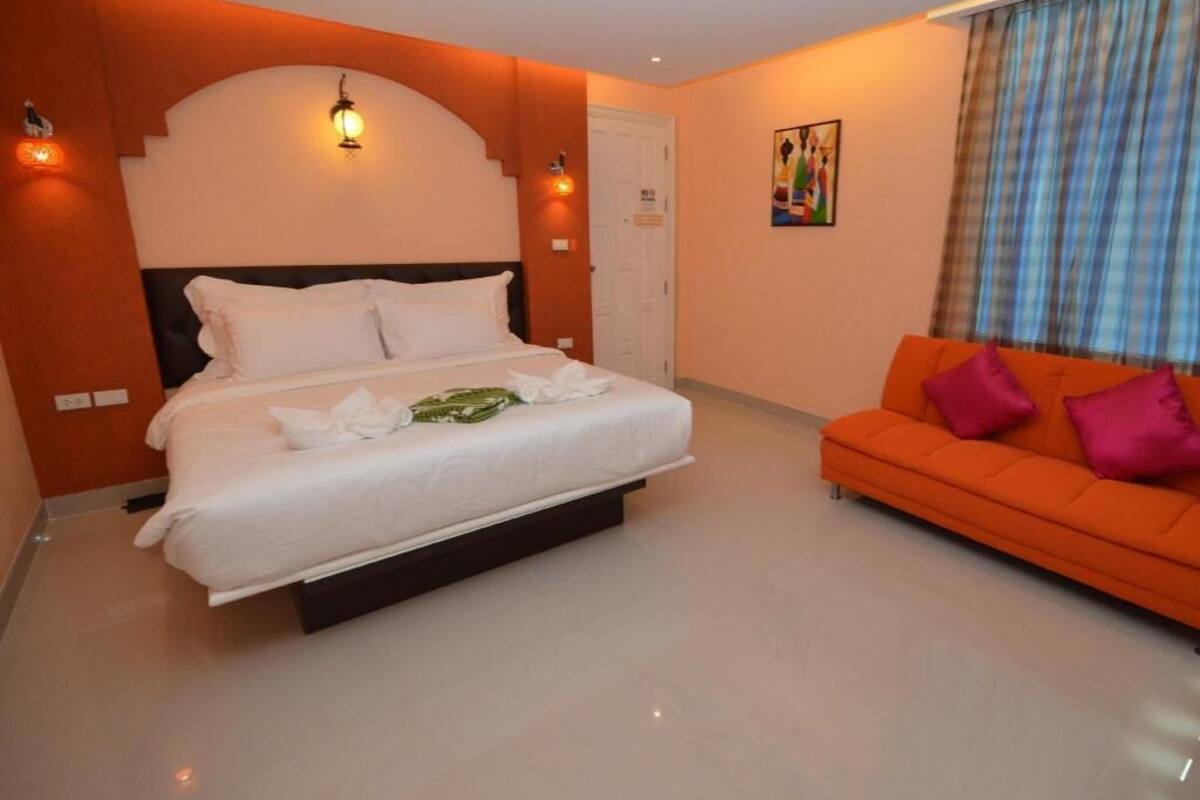 A hotel room with a bed, a sofa, and a painting on the wall.