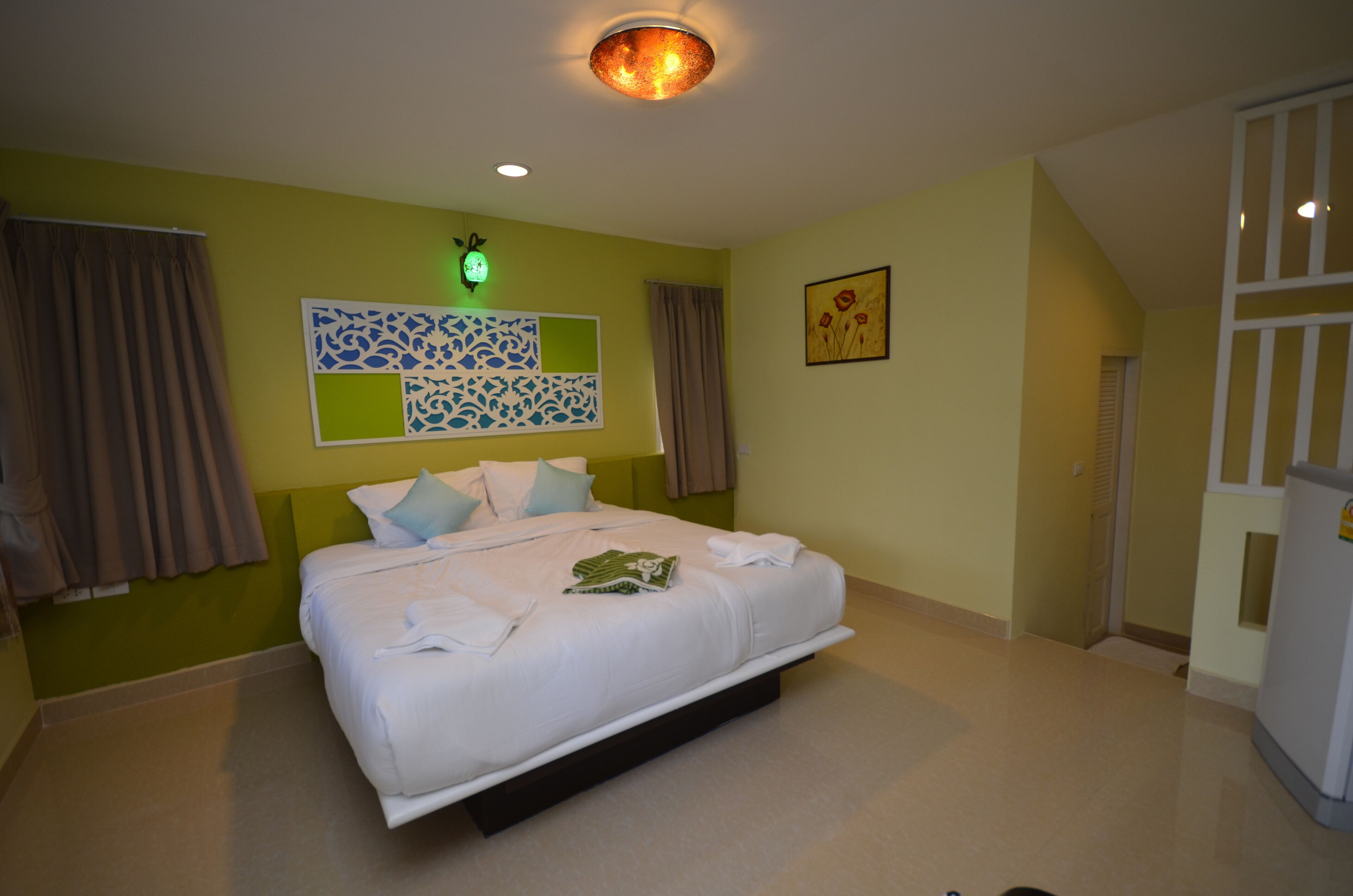 A hotel room with a bed, a green wall, a clock, and a door.