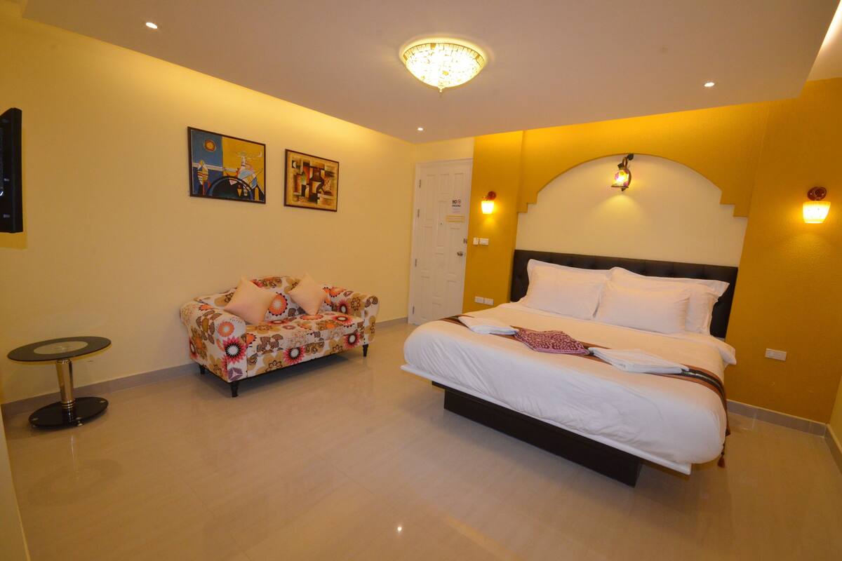 A bedroom with a bed, a sofa, and a small table.