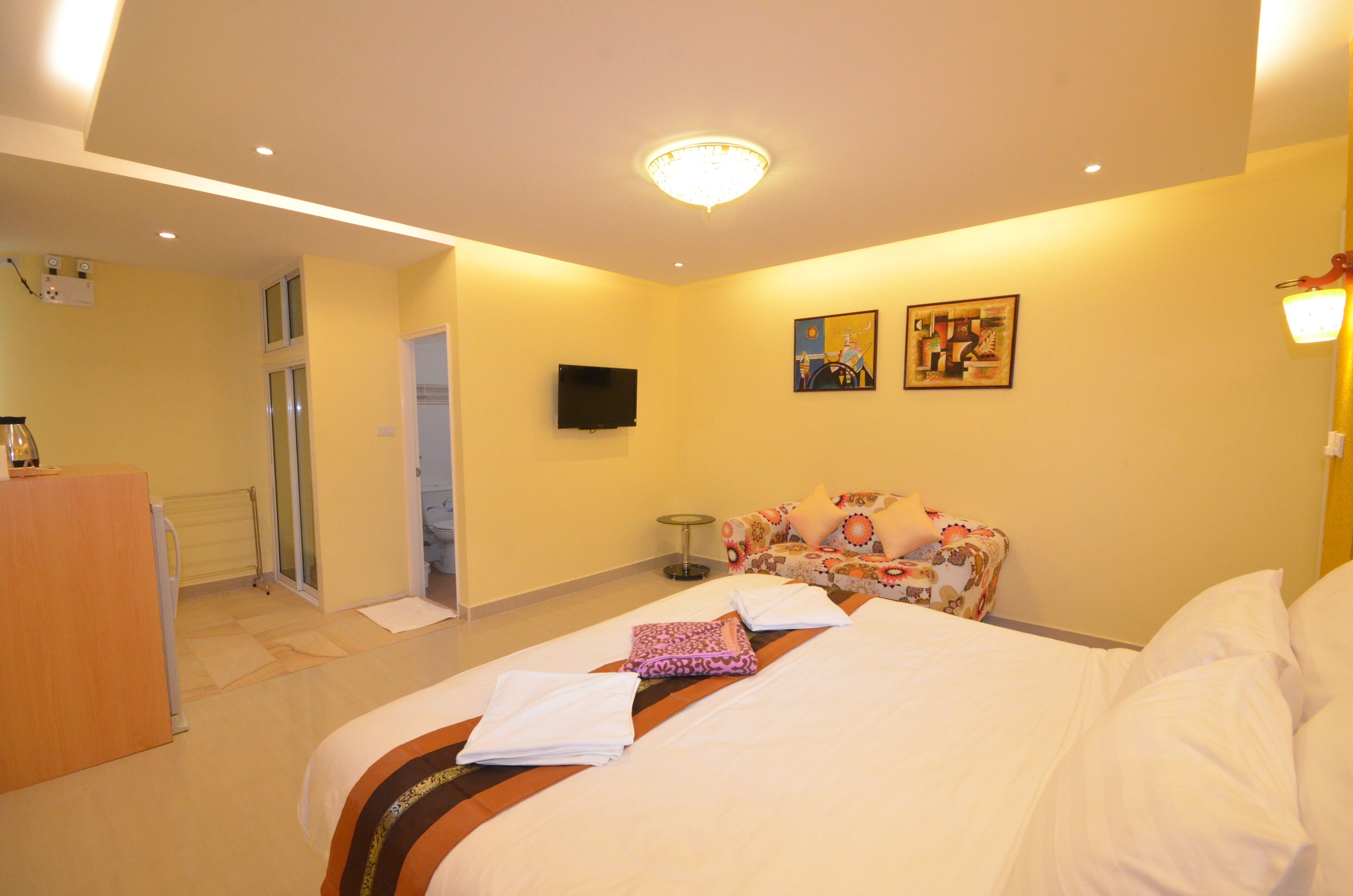 A hotel room with a bed, a television, a painting, and a desk.