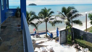 Een balkon met uitzicht op het strand, palmbomen en een eiland in de verte.