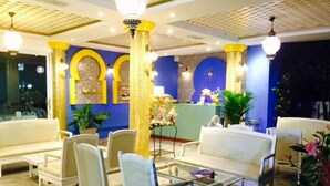 Een hotel lobby met zithoeken, een receptiebalie en decoratieve zuilen.