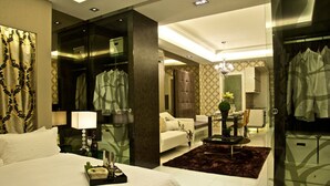 A modern hotel room with a large bed, a seating area with a coffee table, and a glass-enclosed wardrobe. - Damas Suites & Residences (Kuala Lumpur)