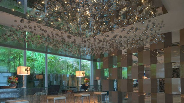 A lobby with a glass wall, a ceiling with hanging ornaments, and a reception desk with chairs. - Damas Suites & Residences (Kuala Lumpur)
