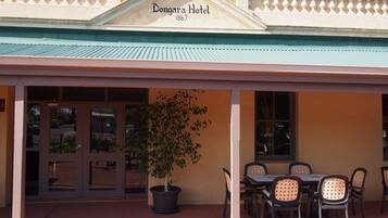 Exterior del Hotel Dongara con un patio cubierto, un árbol en maceta y asientos al aire libre.