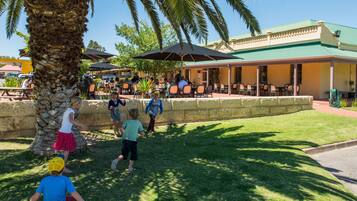 Guests can dine al fresco under shaded umbrellas and a majestic palm tree.