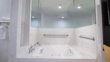 Ein Badezimmer mit einer großen Badewanne, einer Duschkabine aus Glas und einer Handstange.