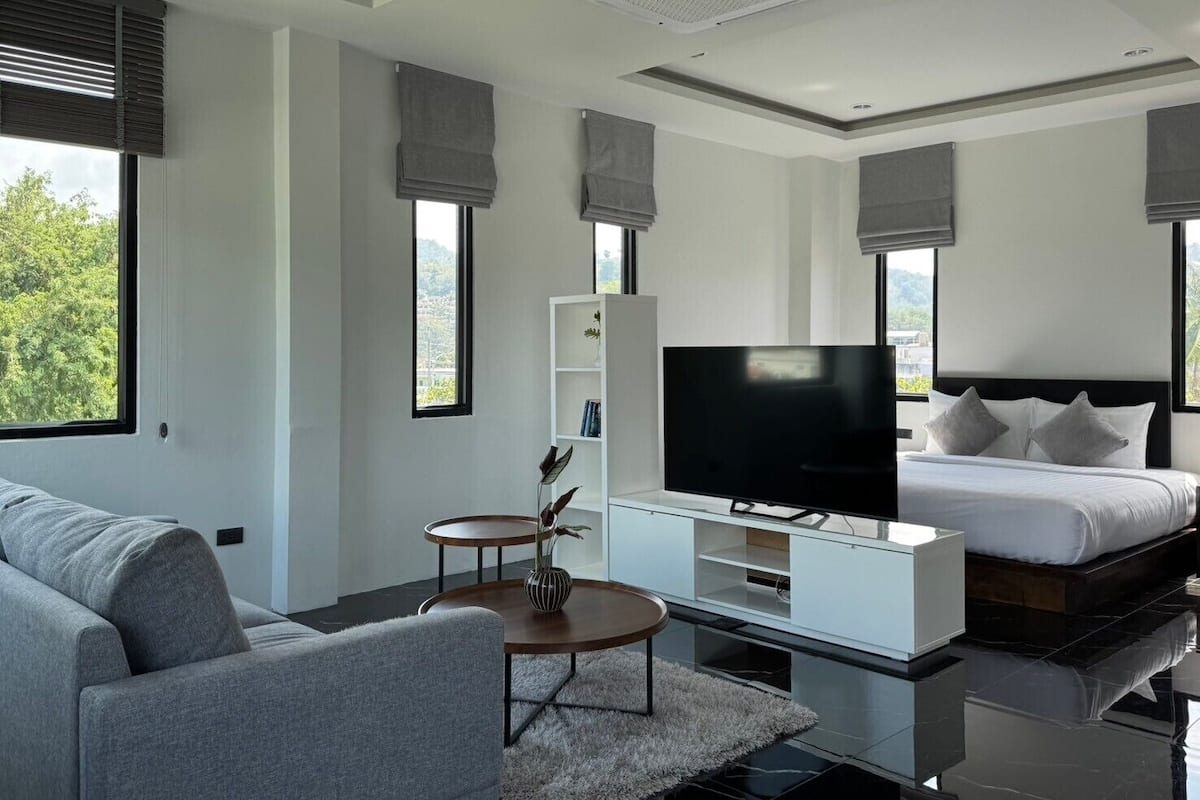 Une chambre d’hôtel moderne équipée d’une télévision à écran plat, d’un canapé, d’une table de chevet et d’un lit.