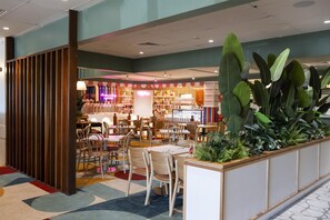 A restaurant with a variety of seating options, including tables and chairs, and a counter area with a display of food items. - Nightcap at Springwood Hotel (Springwood)