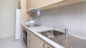 A modern kitchen with a stainless steel sink, wooden cabinets, and a built-in oven.