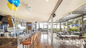 A modern bar area with a long counter, bar stools, and a view of the outdoors.