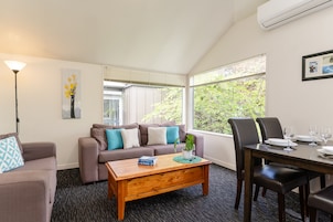 A modern living room with a sofa, coffee table, and dining table set for four.