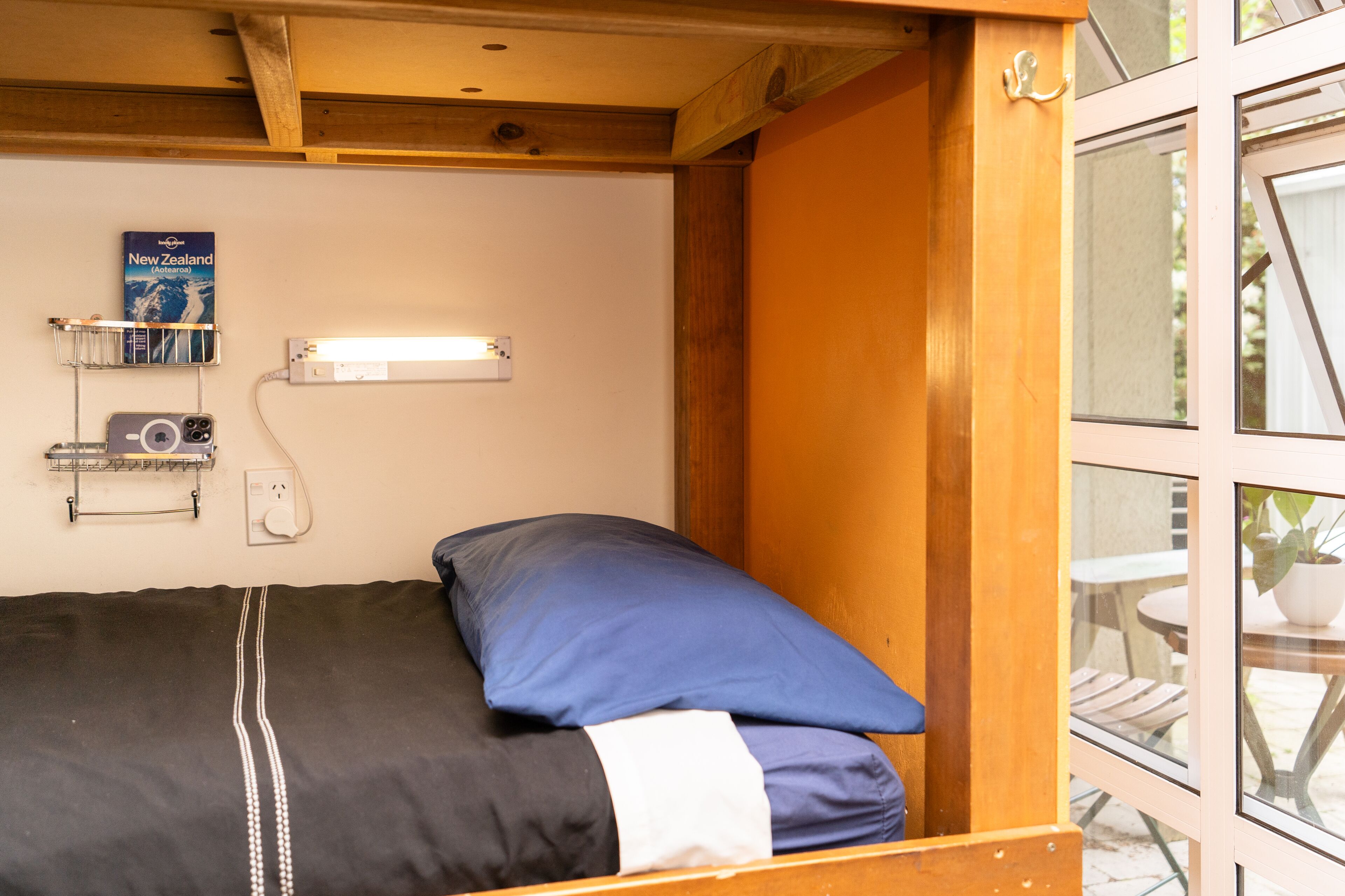 A compact room with a bed, a map on the wall, and a window.