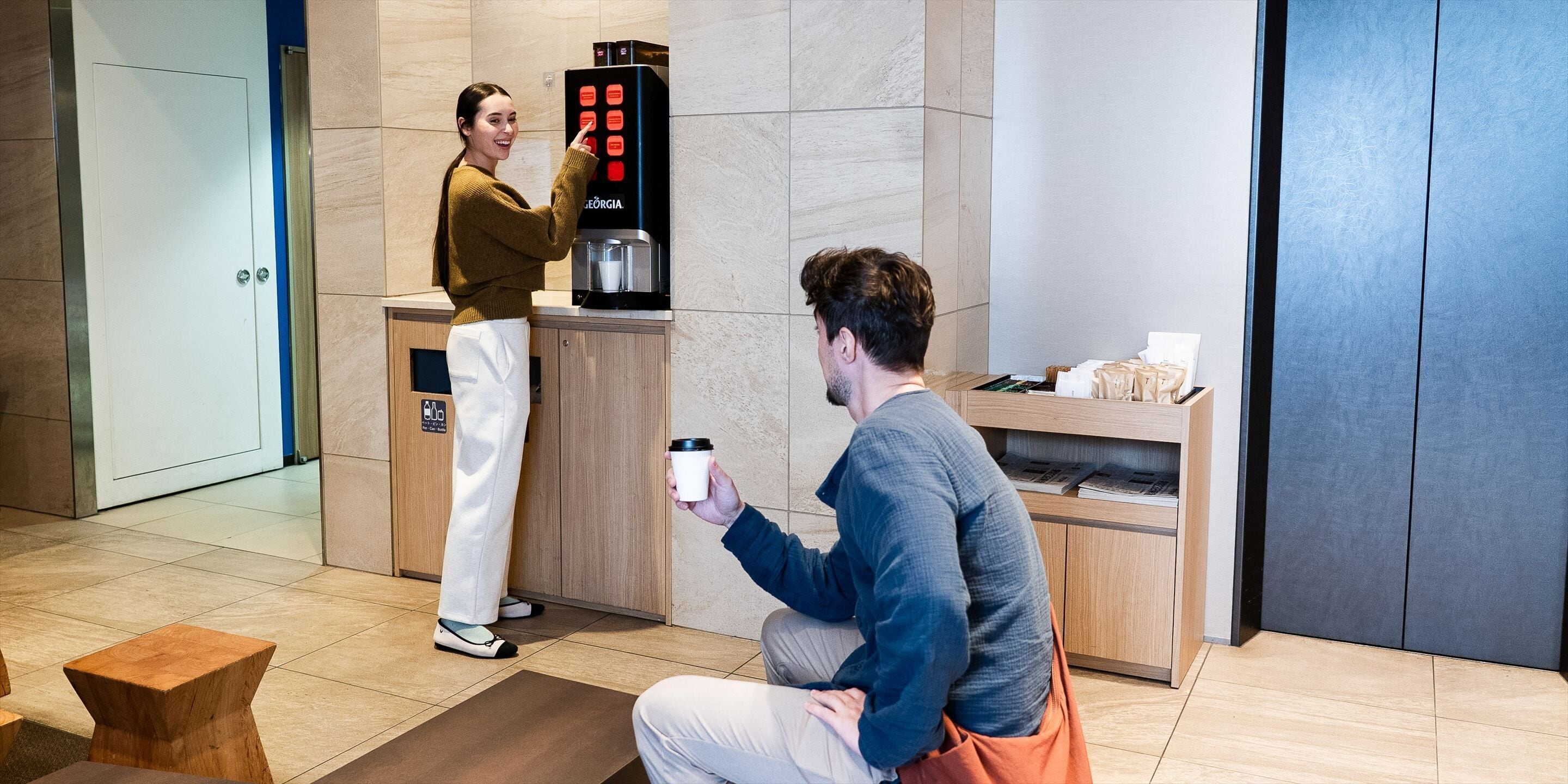 Une machine à café, un comptoir et une personne tenant une tasse.