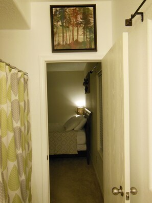 Una camera da letto con un letto, un comodino, una lampada e un quadro appeso al muro.