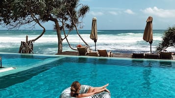 Una piscina techada, una piscina al aire libre, sombrillas