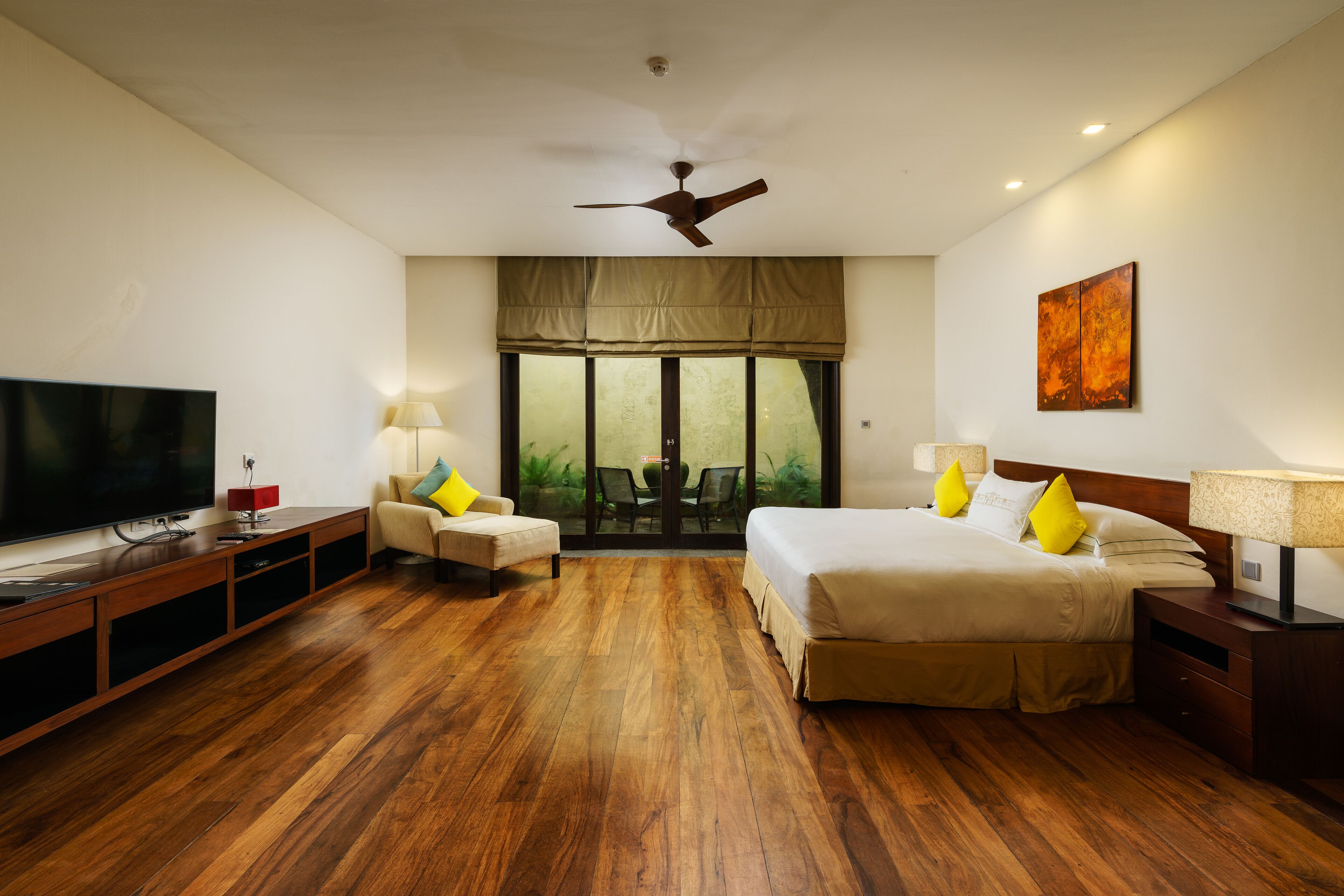 A hotel room with a large bed, a TV, a sofa, and a dining table.