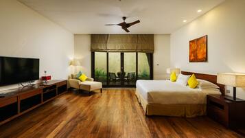 A hotel room with a large bed, a TV, a sofa, and a dining table.