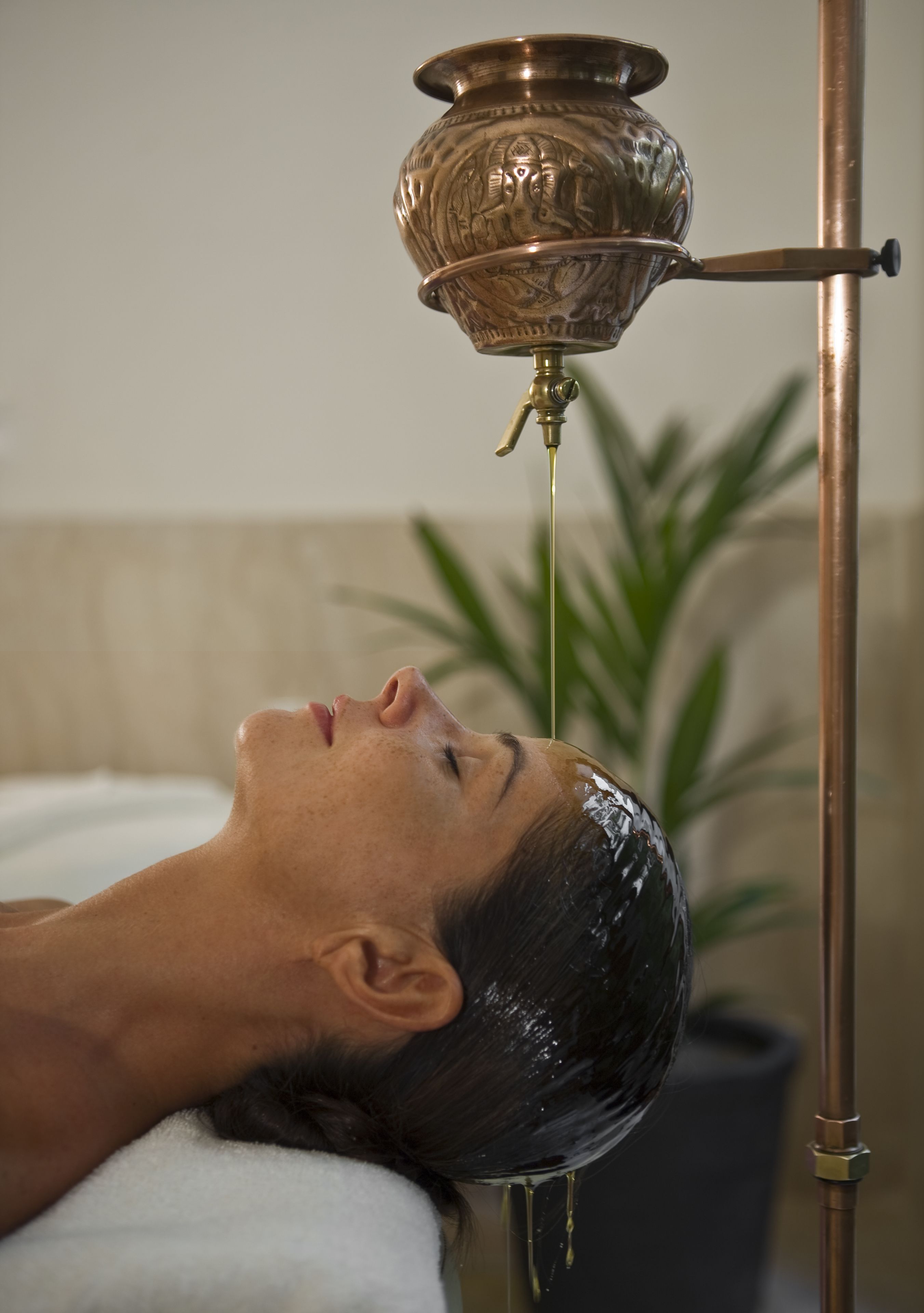 A person receiving a head massage with a metallic head massager.