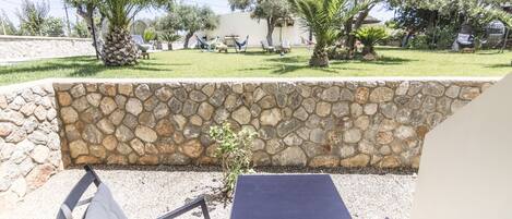 An outdoor seating area with stone walls, a table, and chairs.