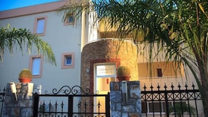 A building with a stone facade, a metal gate, and potted plants. - Lindos Blue Sky (Rhodes)