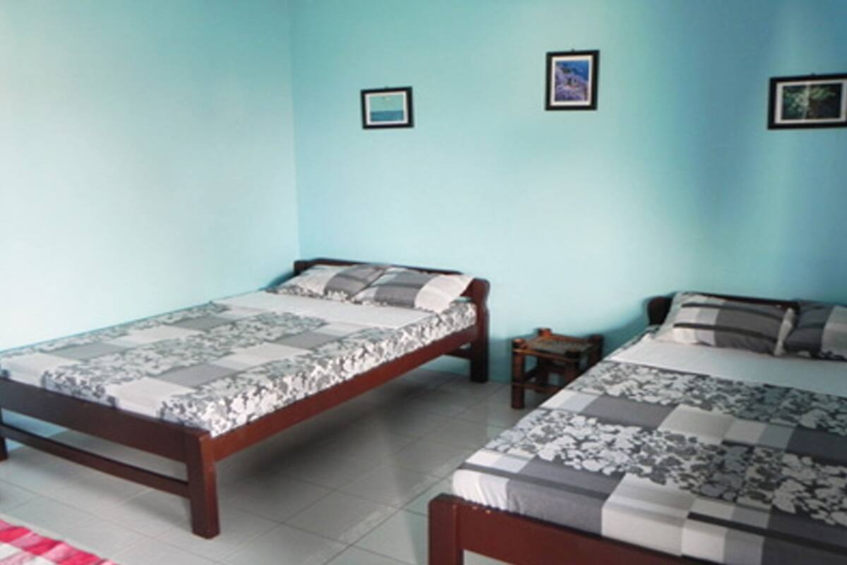 Ein Schlafzimmer mit zwei Betten, einem kleinen Tisch und zwei gerahmten Bildern an der Wand.