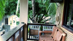 A covered outdoor seating area with wooden furniture and a view of tropical vegetation. - Boracay Actopia Resort (Boracay Island)