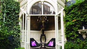 An open garden area with a white gazebo, two black chairs with purple cushions, and a chandelier. - Canal House (Amsterdam)