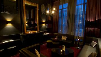 A dimly lit lounge area with a grand mirror, a piano, and a sofa set.
