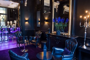Uma área de estar luxuosa com assentos de couro, um bar e um espelho refletindo o ambiente.