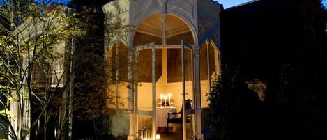 A gazebo with a table set for dining, surrounded by lanterns.