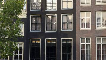 Um edifício de vários andares com fachada preta e detalhes brancos. O andar térreo possui uma placa com a inscrição 'CANAL HOUSE'.