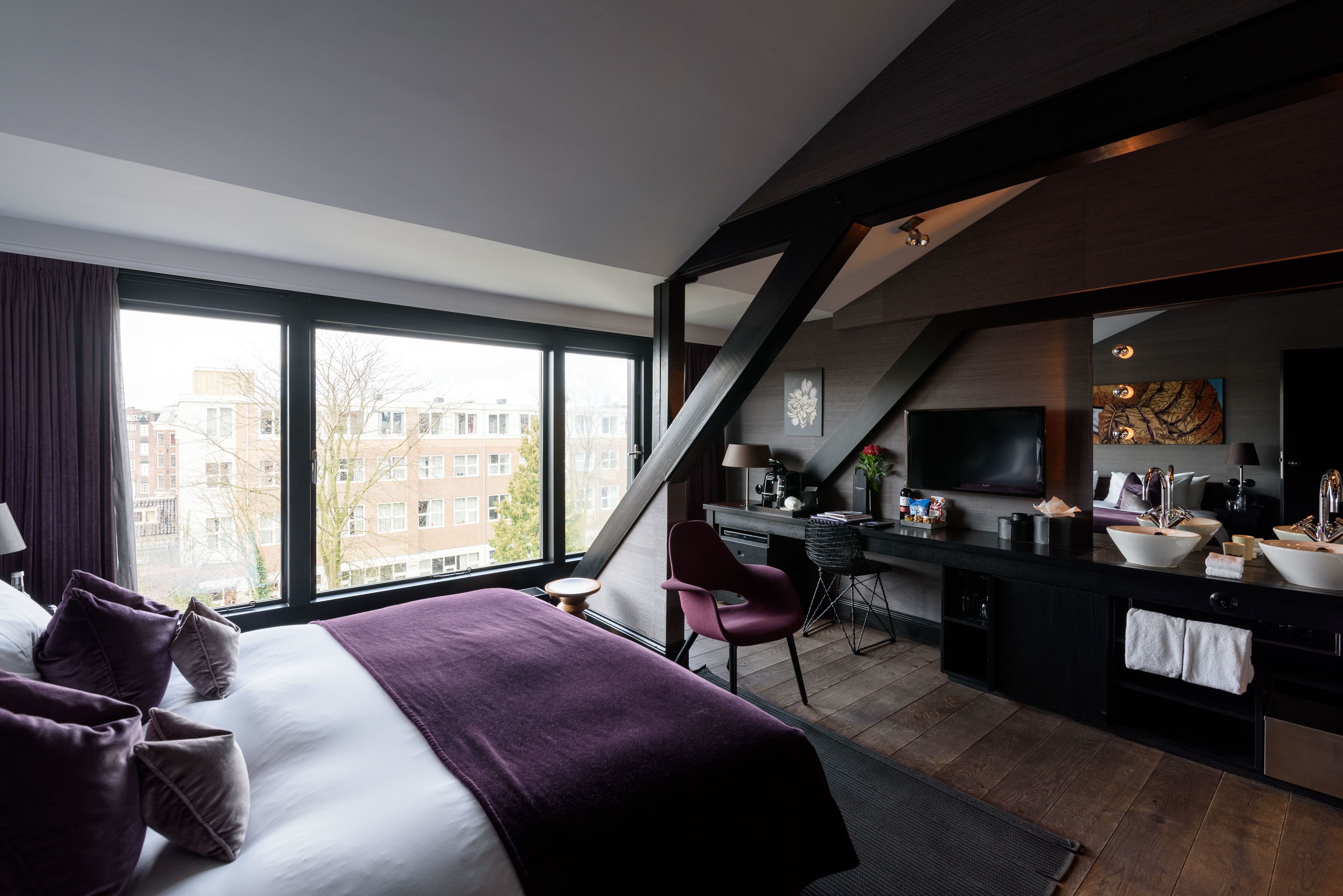 Una habitación de hotel moderna con una cama grande, un escritorio, una kitchenette y un televisor.