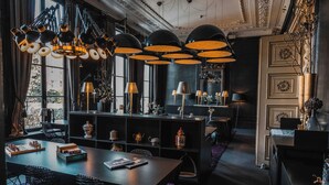 A modern dining area with a long table, multiple chairs, and a variety of decorative items including a chessboard, books, and a vase. - Canal House (Amsterdam)