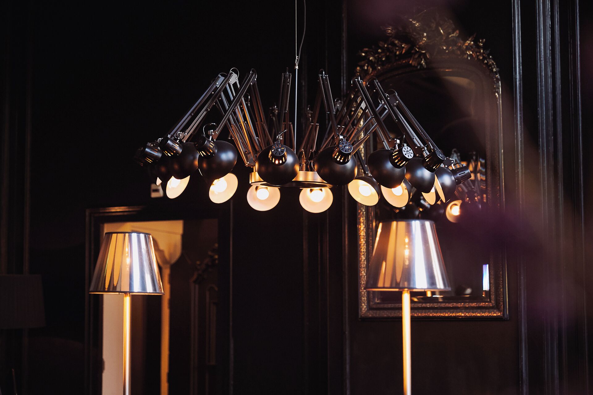 A chandelier with multiple light fixtures and a mirror in the background.