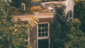 A rustic building with a brick facade, a large window, and a door. - Canal House (Amsterdam)