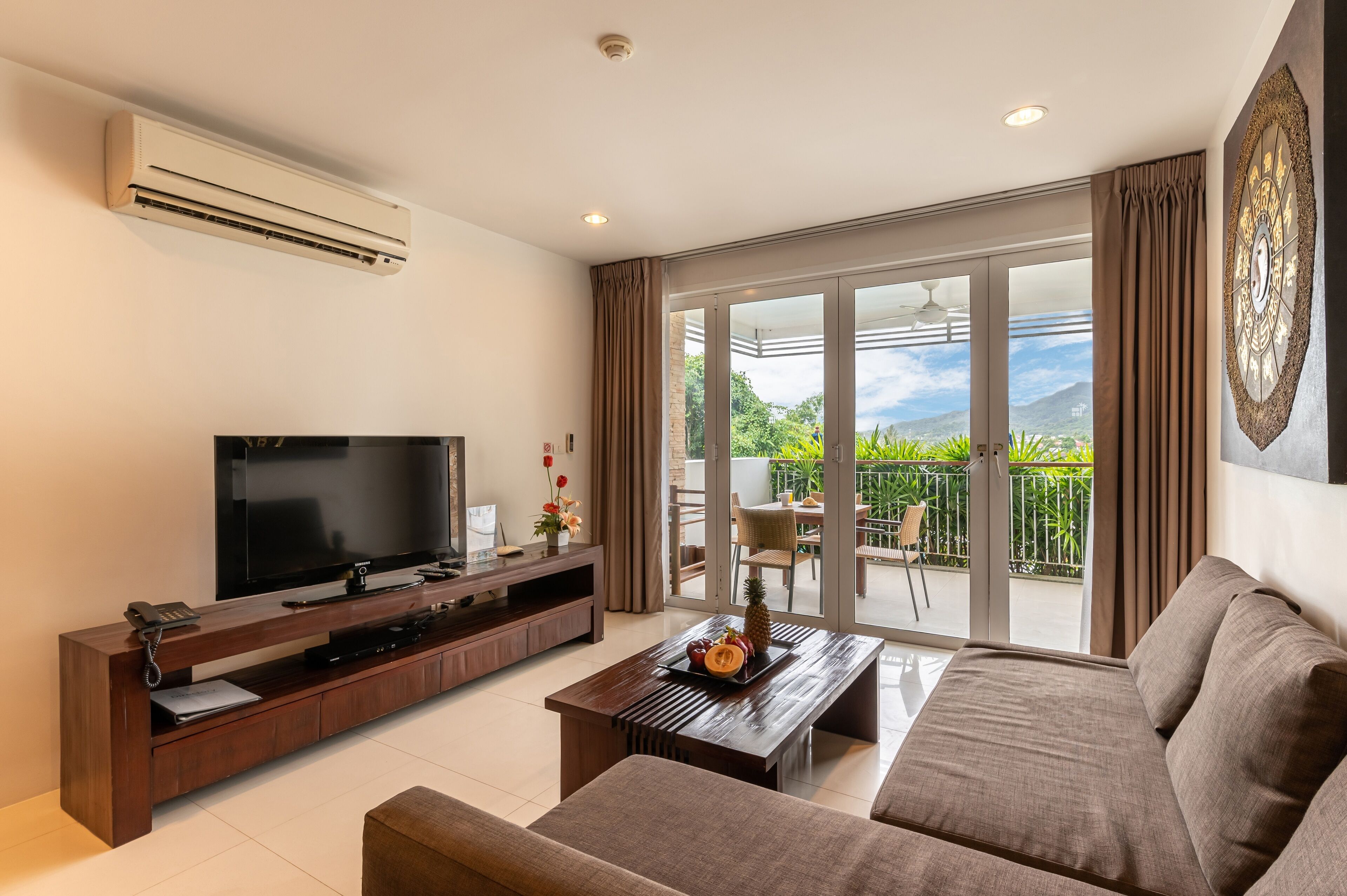 A modern living room with a flat-screen TV, wooden entertainment unit, and a sofa.