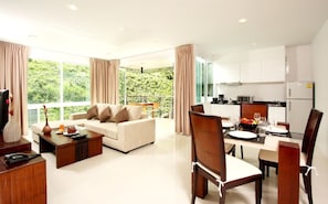 A modern living room with a sofa, coffee table, and dining area with chairs and a table set for a meal.