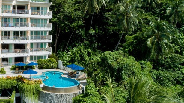A multi-story hotel with a pool area surrounded by lush greenery and palm trees. - The Park Surin by RESAVA (Choeng Thale)