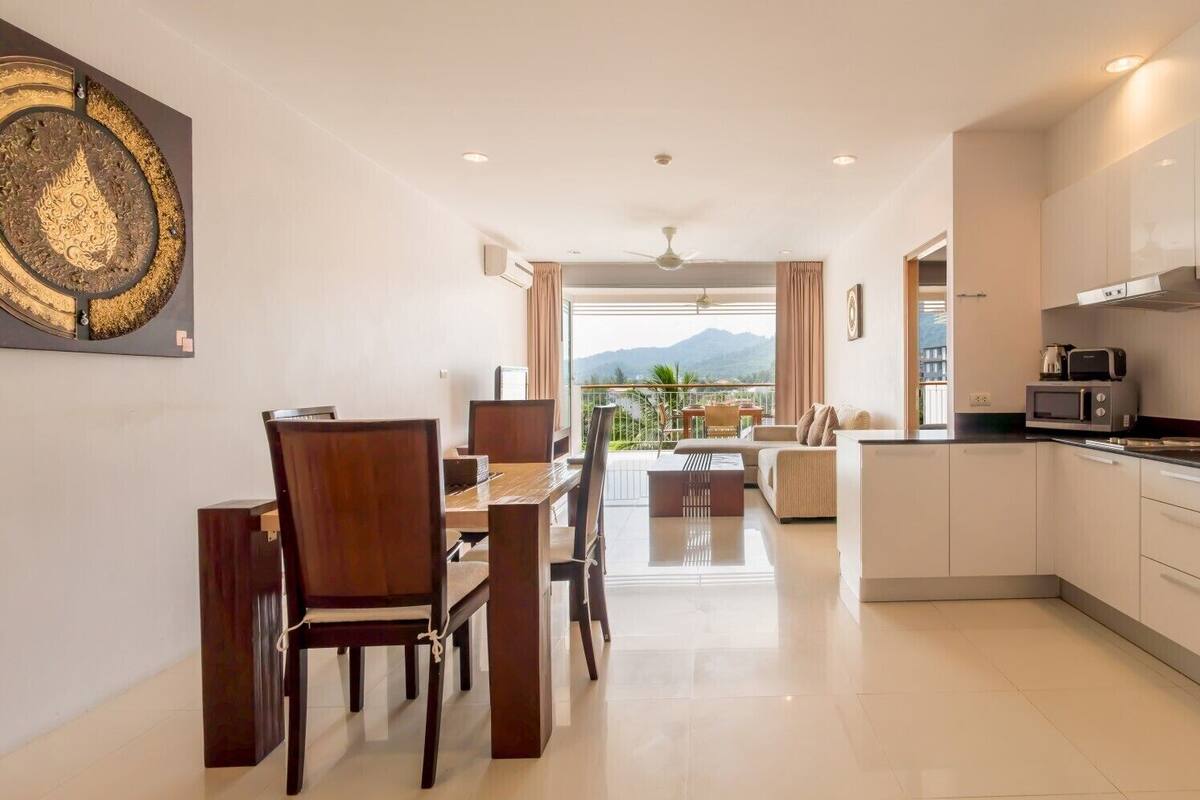 A modern kitchen with a dining area and a view of mountains.