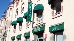 A hotel facade with multiple green awnings and signs indicating 'Le Chatel Hotel Restaurant'.