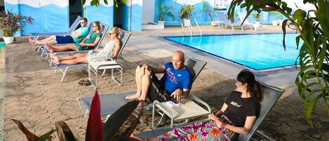 Un área al lado de la piscina con sillones de descanso y una piscina.