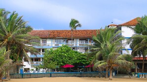 A beachfront hotel with multiple balconies, palm trees, and a sandy beach. - Topaz Beach Hotel (Negombo)