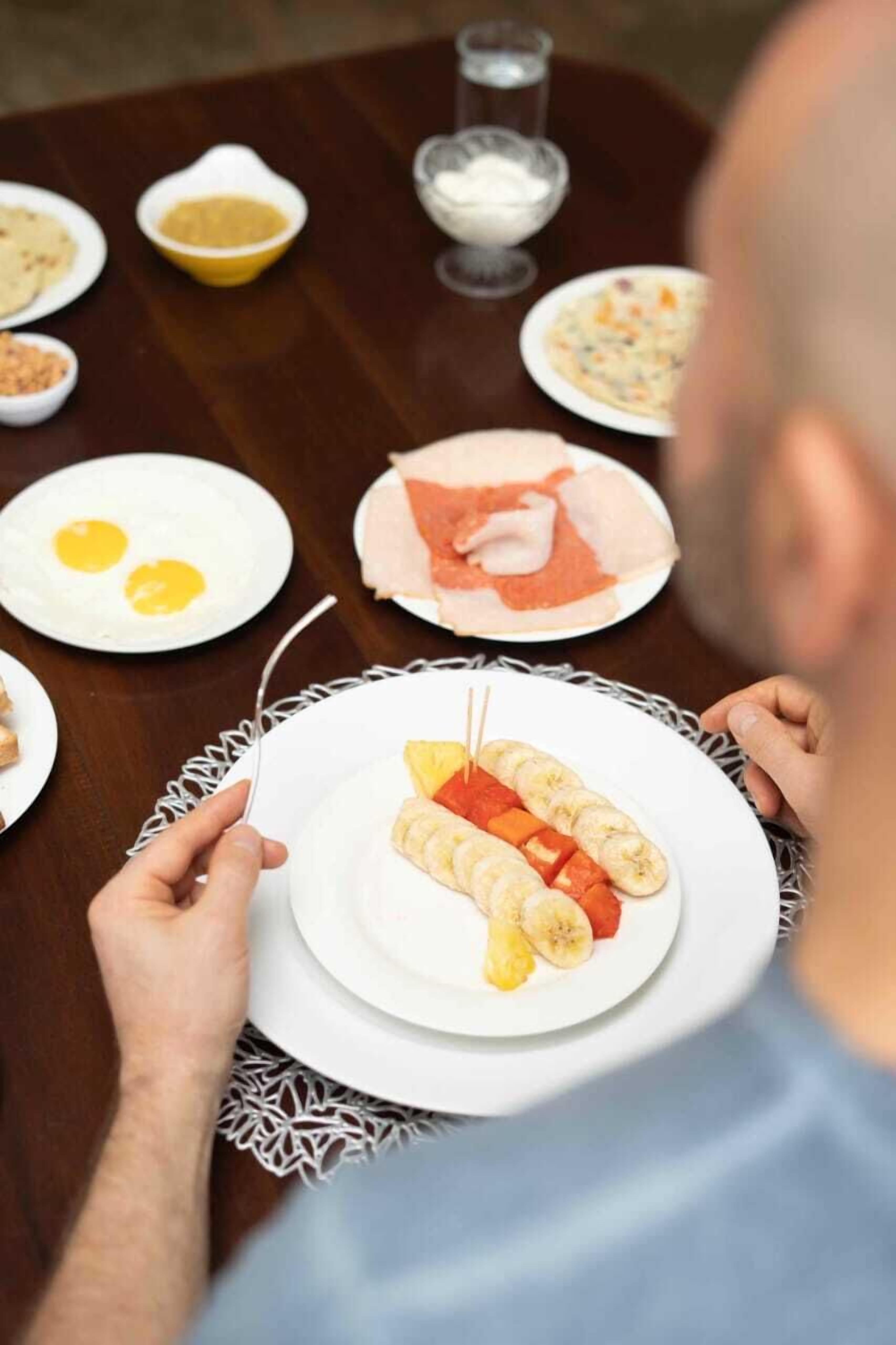 A dining table with various dishes including eggs, ham, and skewered vegetables.