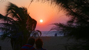 A sunset view from a balcony overlooking a beach with palm trees. - Topaz Beach Hotel (Negombo)